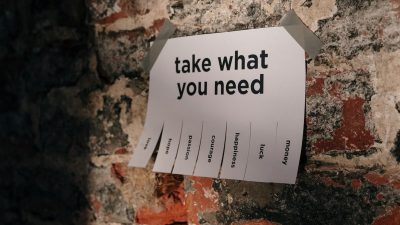 A motivational note offering positive qualities taped to a brick wall.